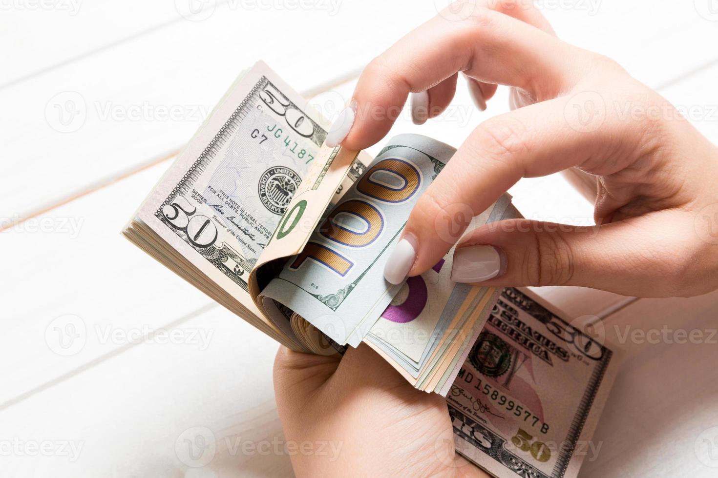 Perspective view of female hands counting money. One hundred and other dollar banknotes on colorful background. Business concept photo