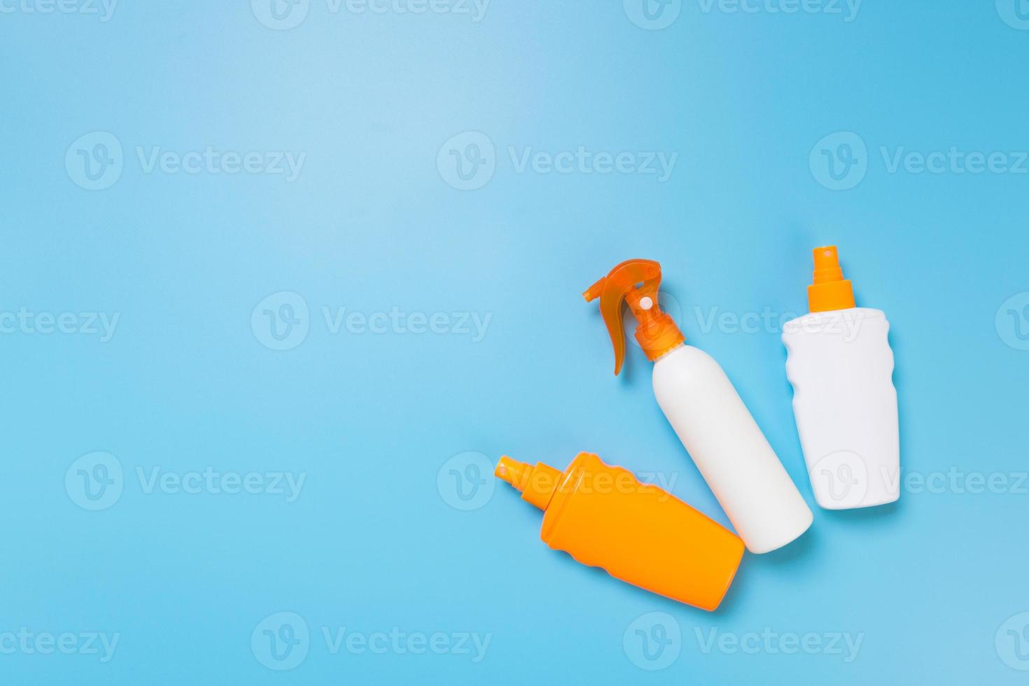 flat lay concept of summer travel vacation. Sunscreen bottle mock up on blue background top view with copy space photo