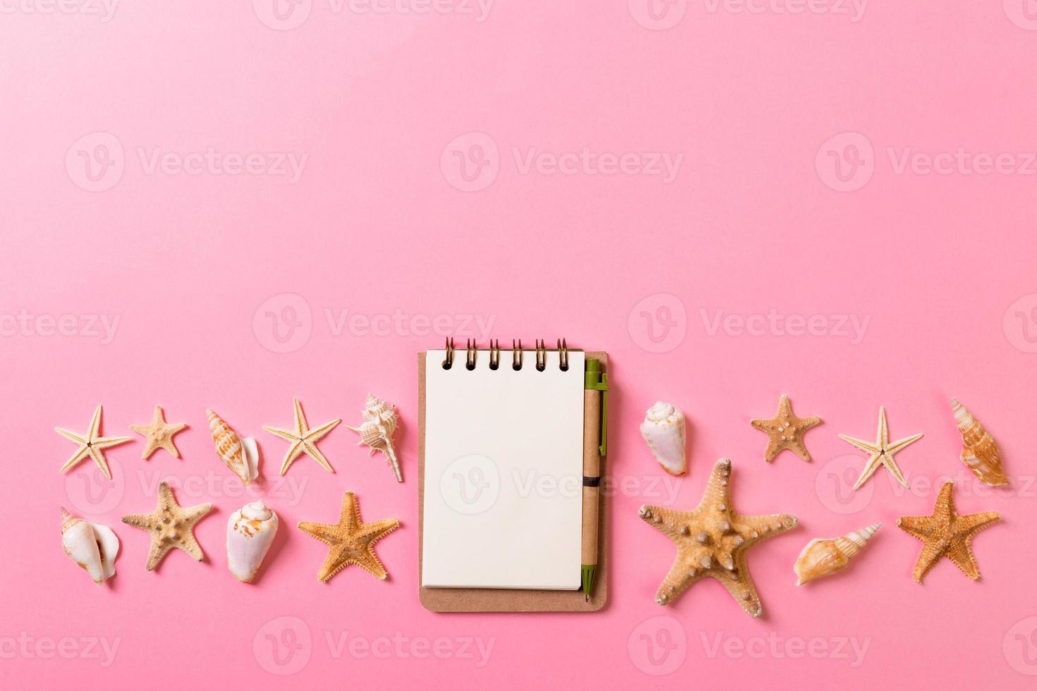 notebook with sseashells on pink background top view flat lay. Planning summer holidays, tourism and vacation concept photo