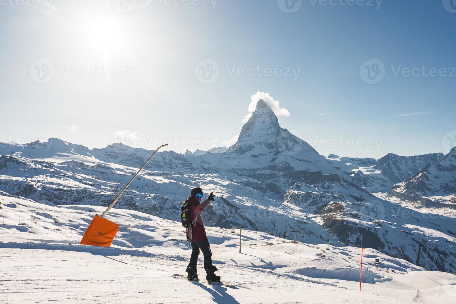 Young man snowboarding in Zermatt ski resort right next to the famous Matterhorn peak. Beautiful sunny day for snowboarding. Winter sports concept. photo