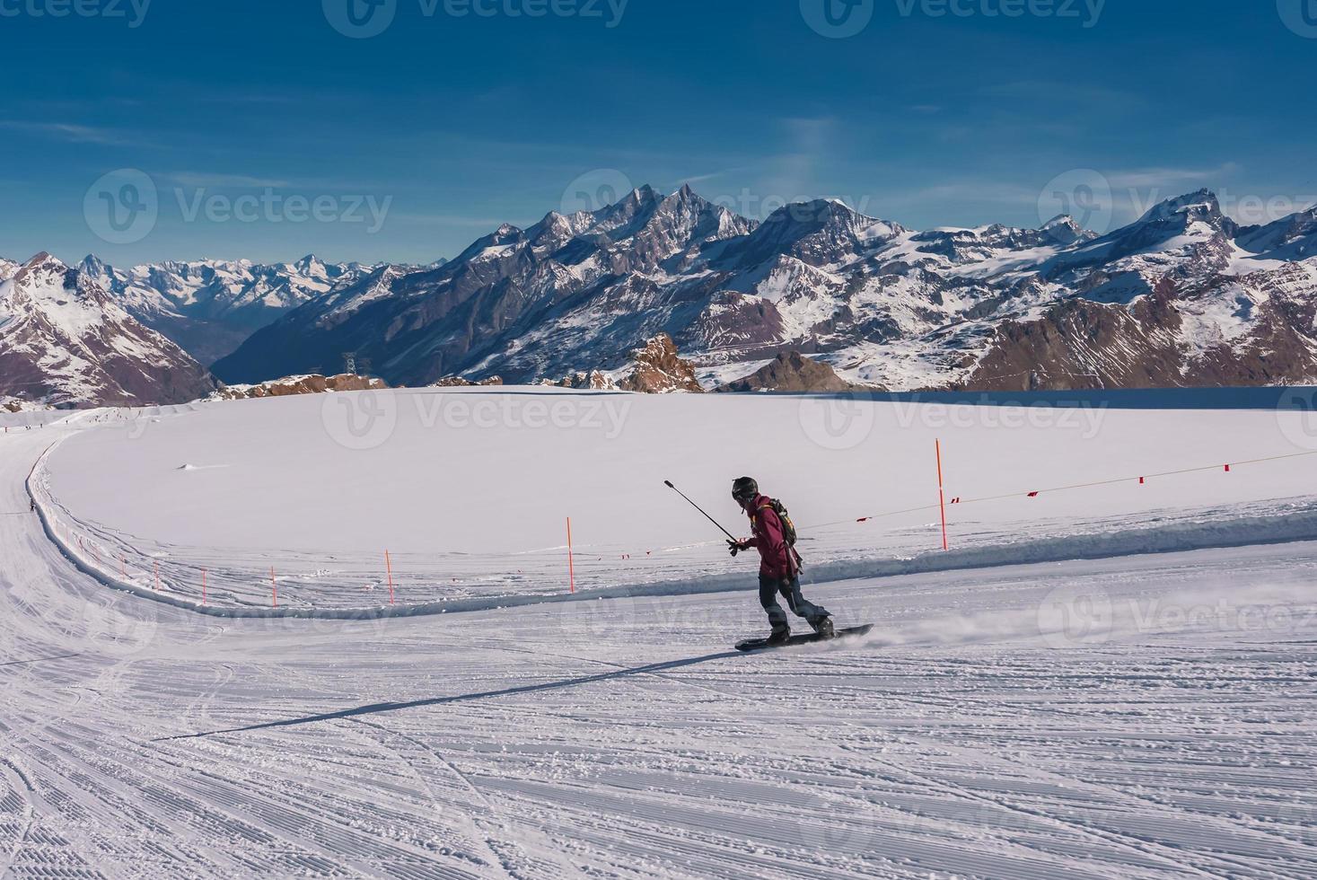 Young man snowboarding in Zermatt ski resort right next to the famous Matterhorn peak. Beautiful sunny day for snowboarding. Winter sports concept. photo