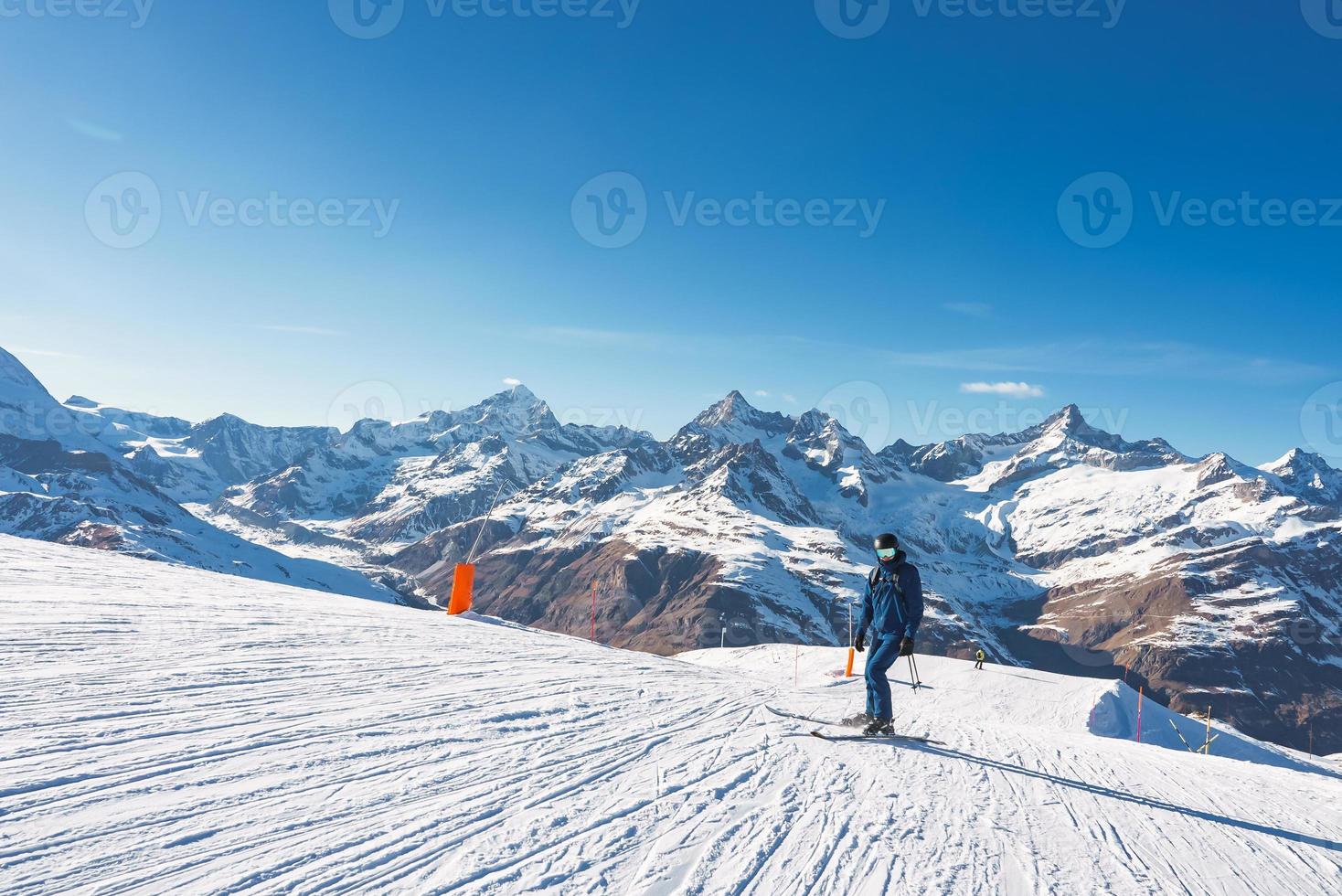 Young man skiing in Zermatt ski resort right next to the famous Matterhorn peak. Beautiful sunny day for snowboarding. Winter sports concept. photo