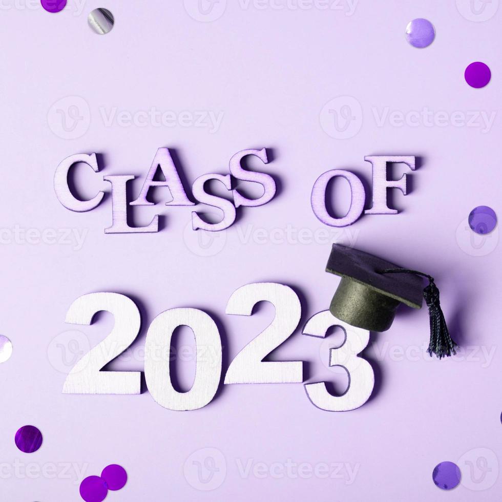 Class of 2023 concept. Wooden number 2023 with graduated cap on colored background photo