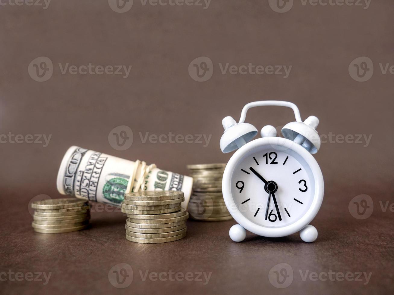 Alarm clock, coins and banknotes on a dark background. The idea of business, Finance concept and saving money and time photo