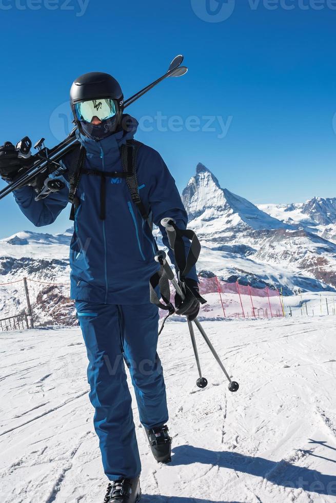 Young skier enjoying Zermatt ski resort. Beautiful sunny day with a skier up in the mountains. Sports model. photo