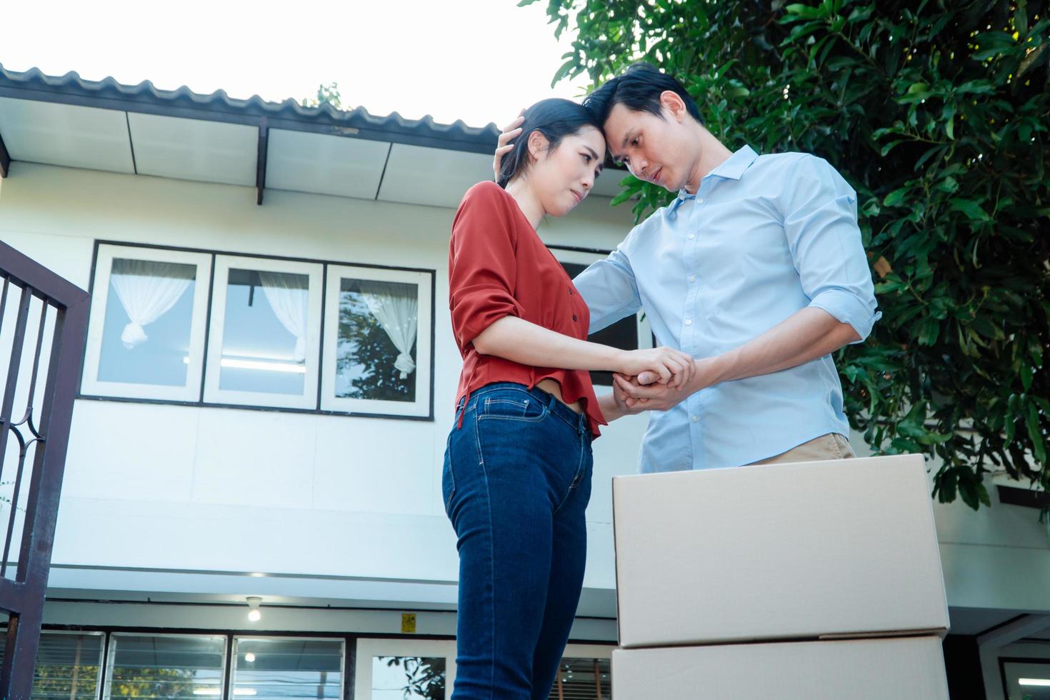 hombre consolando a su esposa y mujer abrazando a su esposo y llorando frente a la casa y llenos de cajas de cartón durante el transporte en el día de la mudanza, concepto de mudanza a casa foto