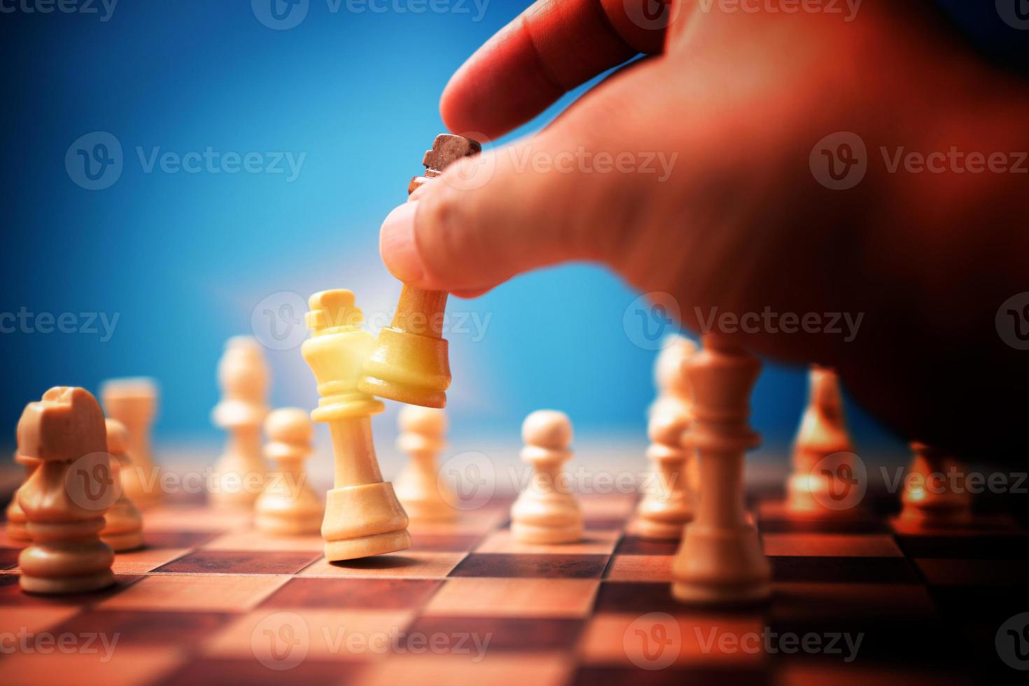 The hand of businessman holding brown king chess and checkmate competitor and win the games. Concept of leadership must have a business strategy and competitor evaluation in competition photo