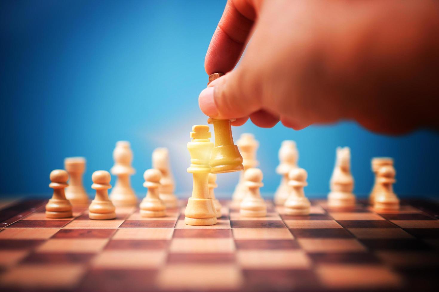 The hand of businessman holding brown king chess and checkmate competitor and win the games. Concept of leadership must have a business strategy and competitor evaluation in competition photo