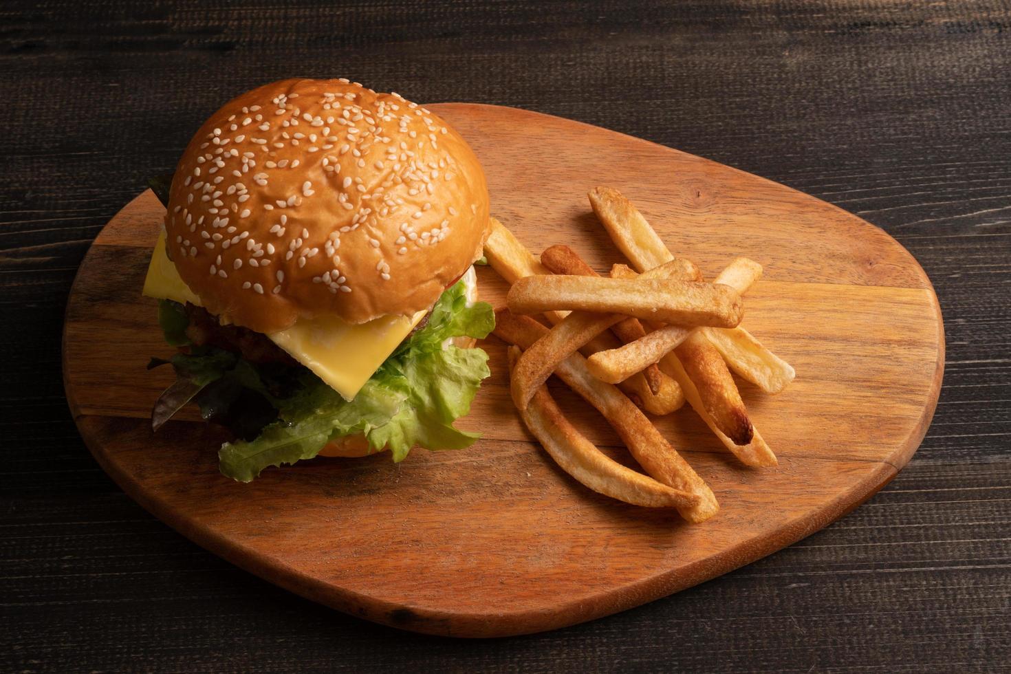 fresh tasty homemade hamburger with fresh vegetables, lettuce, tomato, cheese on a cutting board with French fries. Free space for text photo