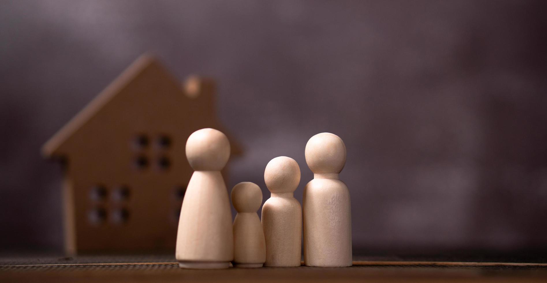 figuras de madera familia de pie frente a una casa de madera. el concepto de protección y seguridad, seguridad en el hogar, seguro de propiedad y casa. foto