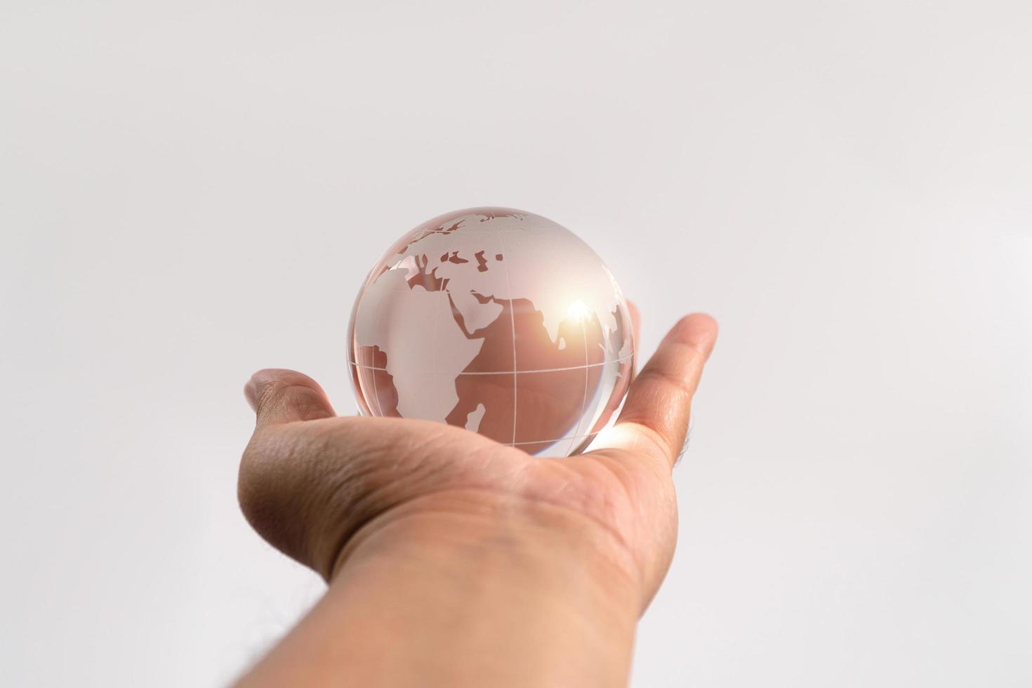 Hand man holding glass earth on isolated background. Concept of caring for the environment and the fragile weakness of the world photo