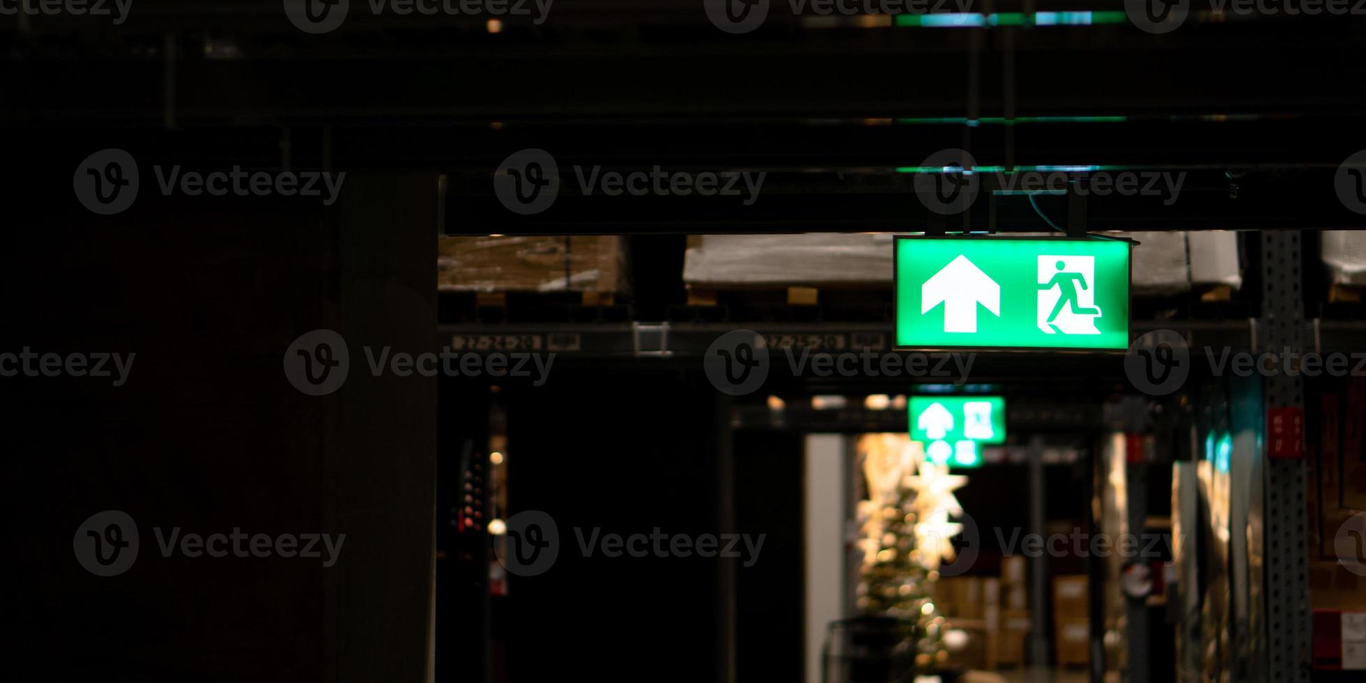 Green fire escape sign hang on the ceiling in the Warehouse. The concept of fire escape training and preparation for evacuation photo