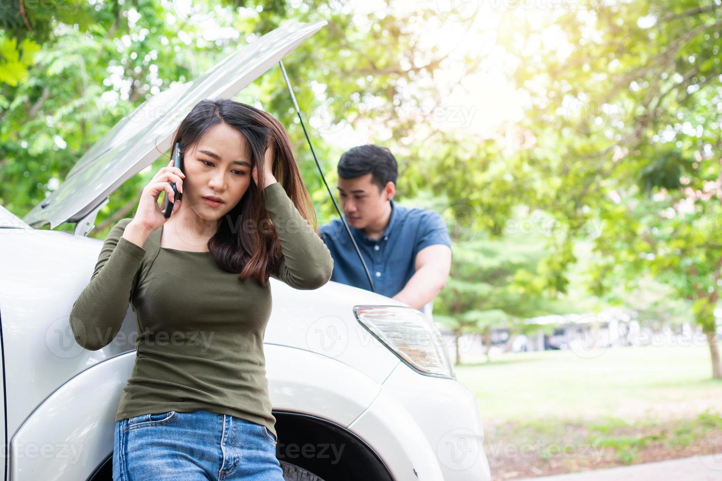 enojado asiático hombre utilizando teléfono inteligente para asistencia después un coche Descompostura en calle. concepto de vehículo motor problema o accidente y emergencia ayuda desde profesional mecánico foto