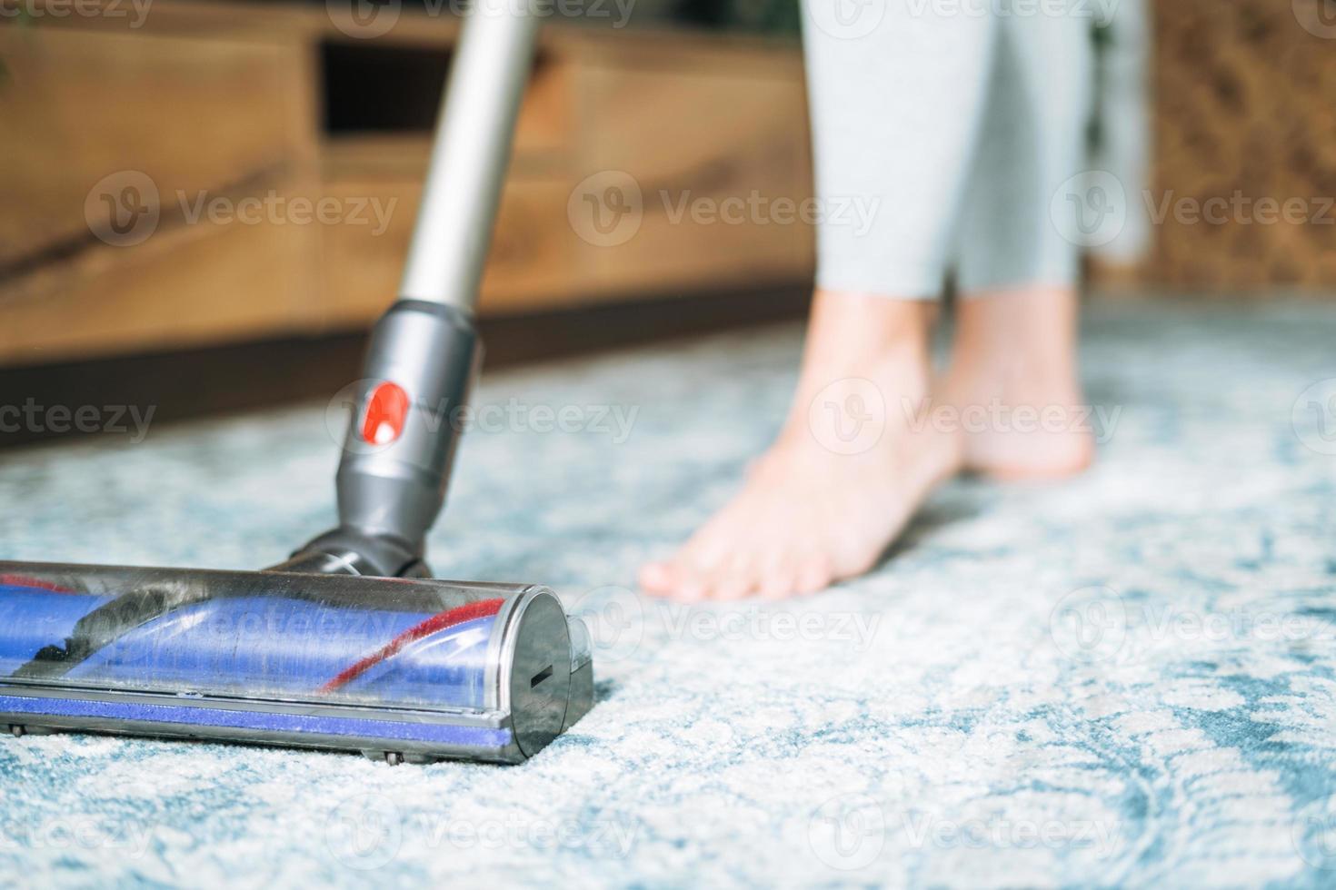 Close up photo of young woman using vacuum cleaner cleaning carpet floor at home