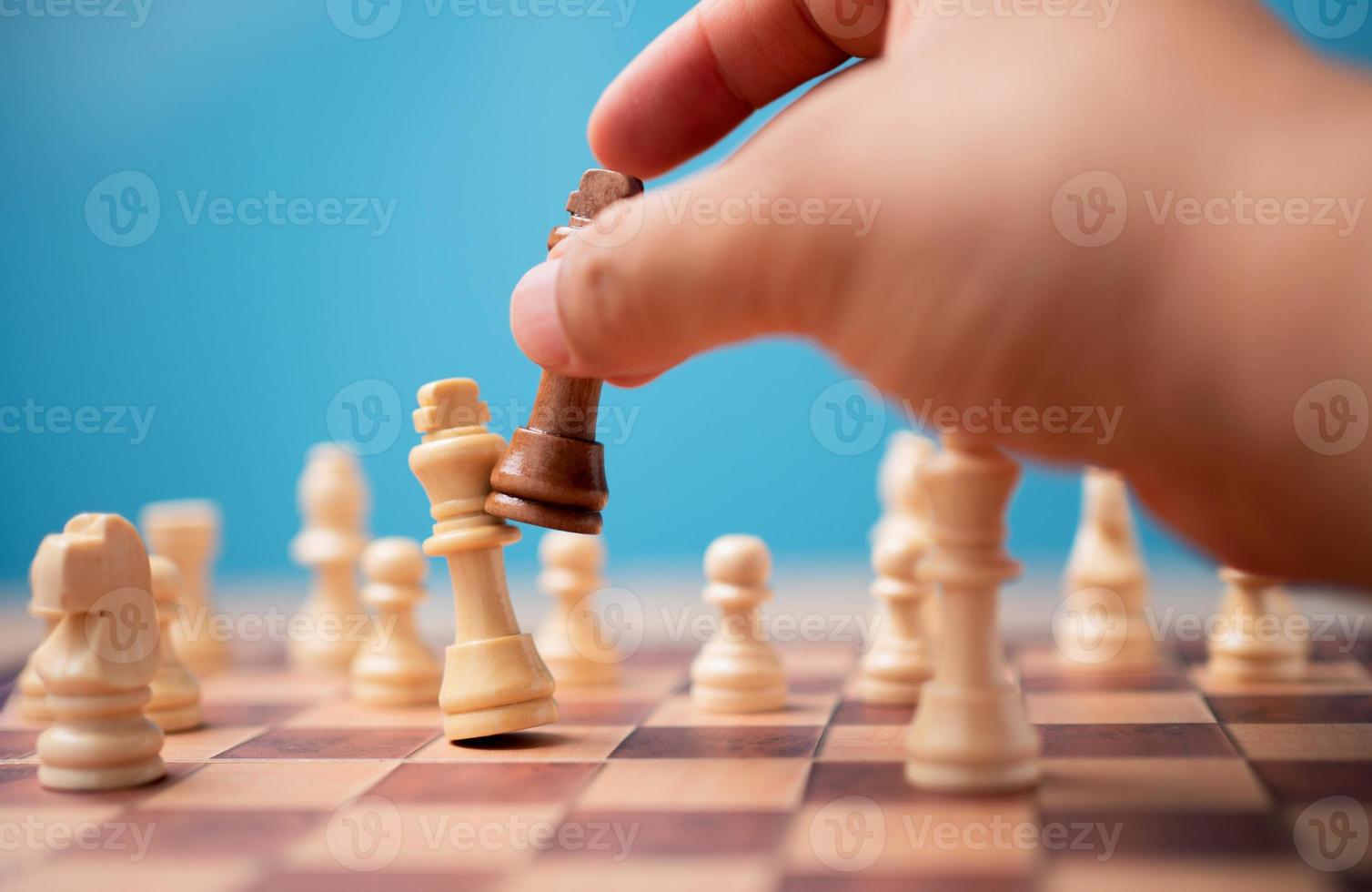 The hand of businessman holding brown king chess and checkmate competitor and win the games. Concept of leadership must have a business strategy and competitor evaluation in competition photo