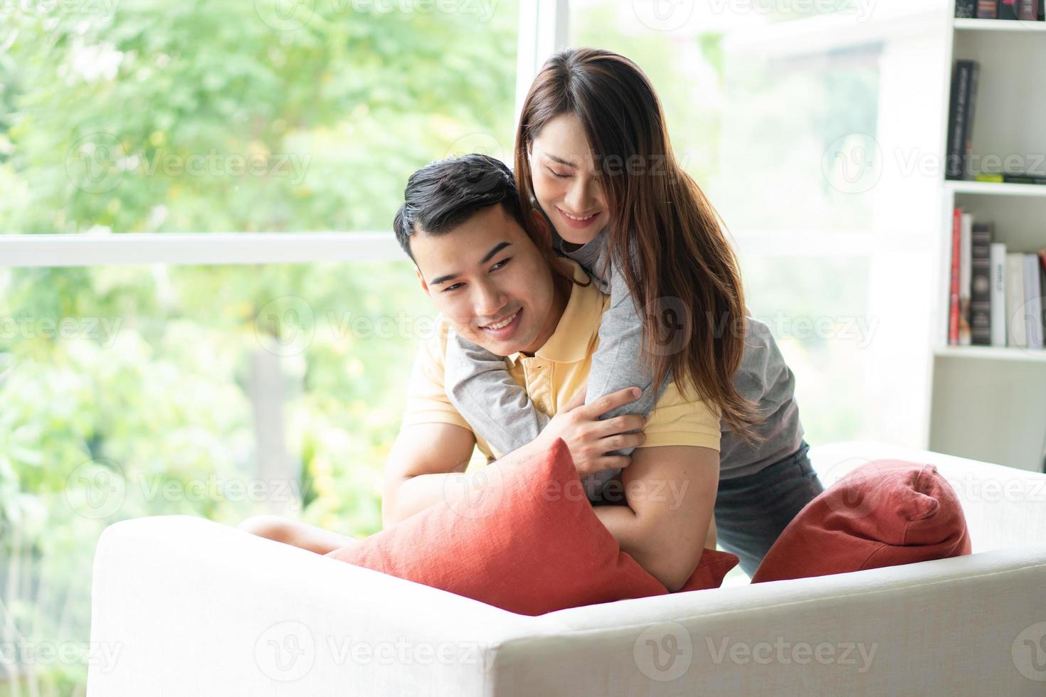 contento Pareja sentado en el sofá y siendo un mujer abrazando su novio con amor en el vivo habitación y sonrisa. concepto de romántico en enamorado día. propuesta y matrimonio foto