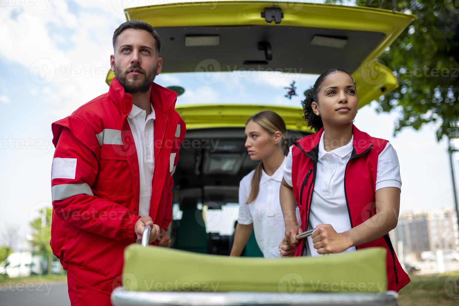 young paramedics moving ambulance stretcher from car in a hurry. Paramedics in uniform taking stretcher out the ambulance car photo