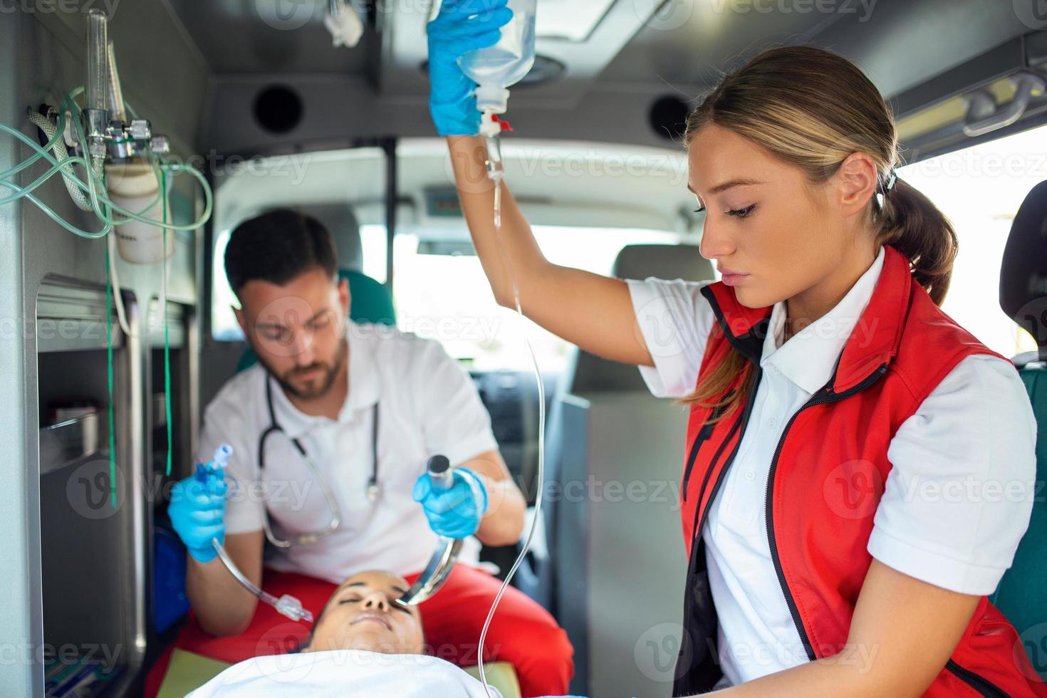 Doctor is ready for endotracheal intubation for non breathing patient. Young female paramedic holding iv solution. EMS Paramedics Provide Medical Help to an Injured Patient on the Way to a Hospital photo