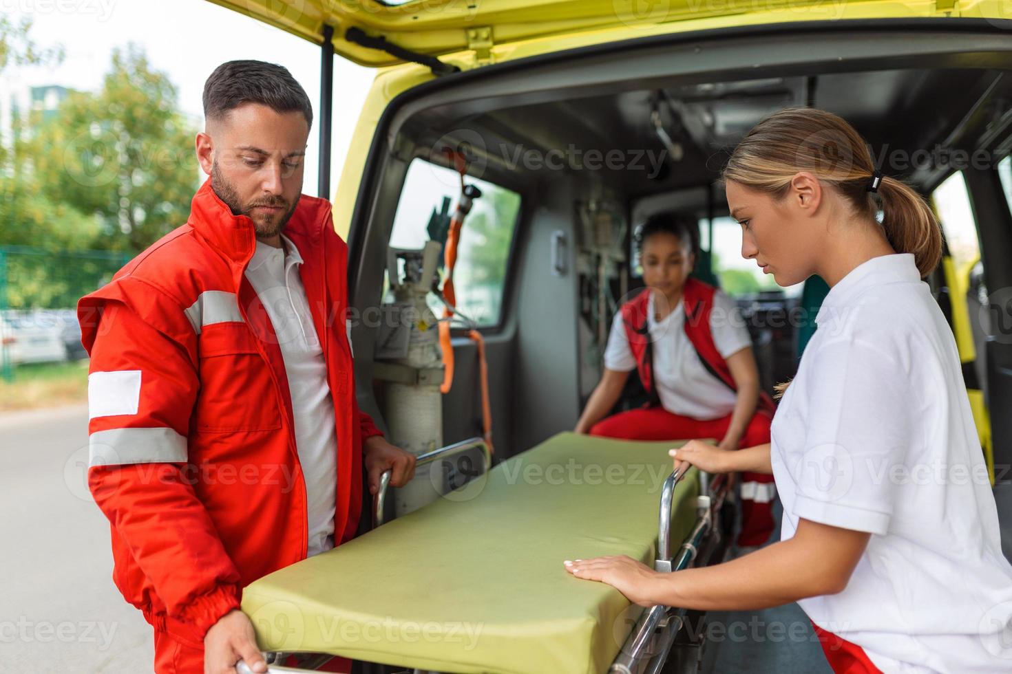 Three paramedics taking out strecher from ambulance photo