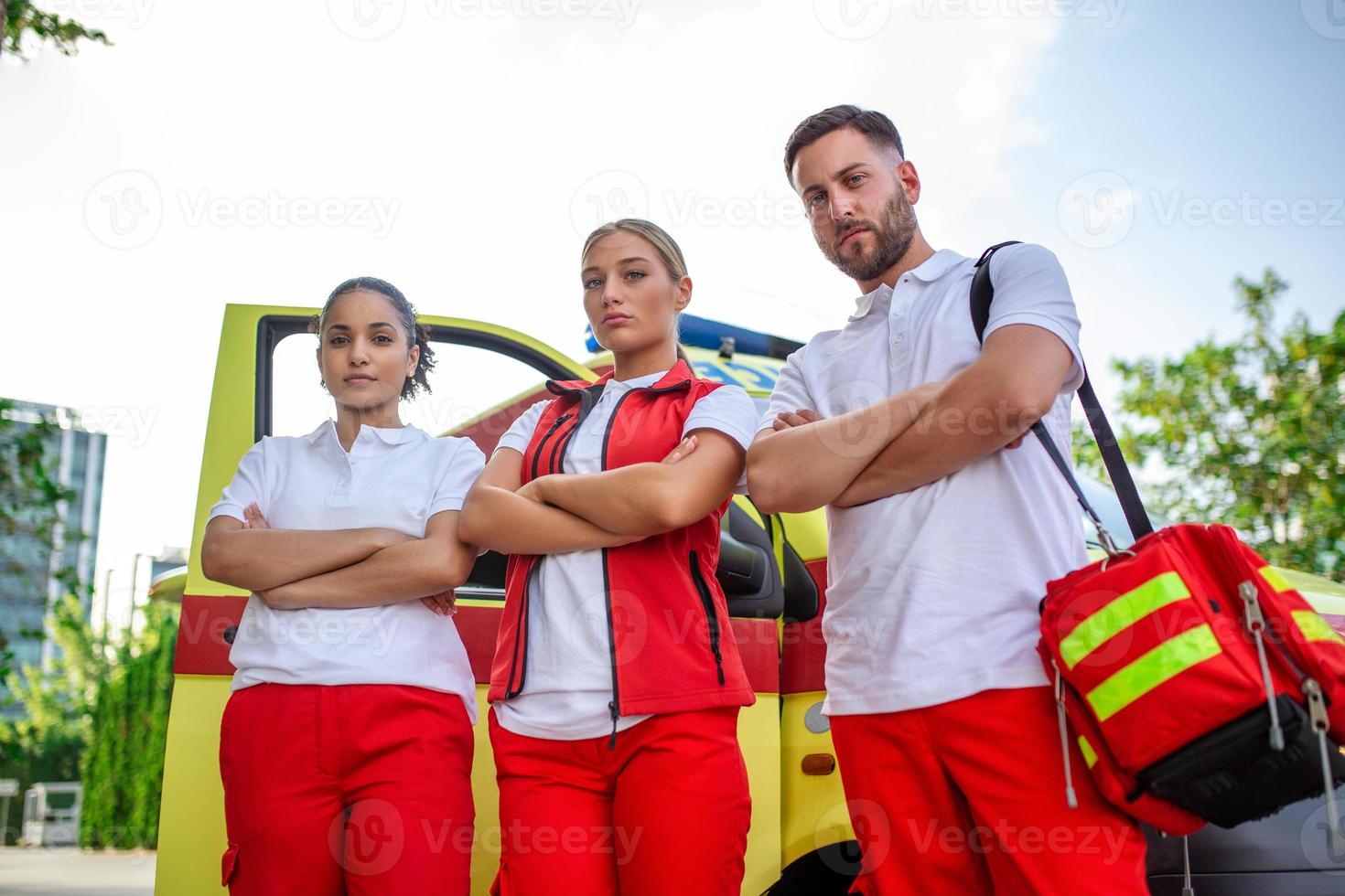 Multi-ethnic paramedics standing at the fromt of an ambulance. Emergency doctor and nurse standing in front of ambulance photo