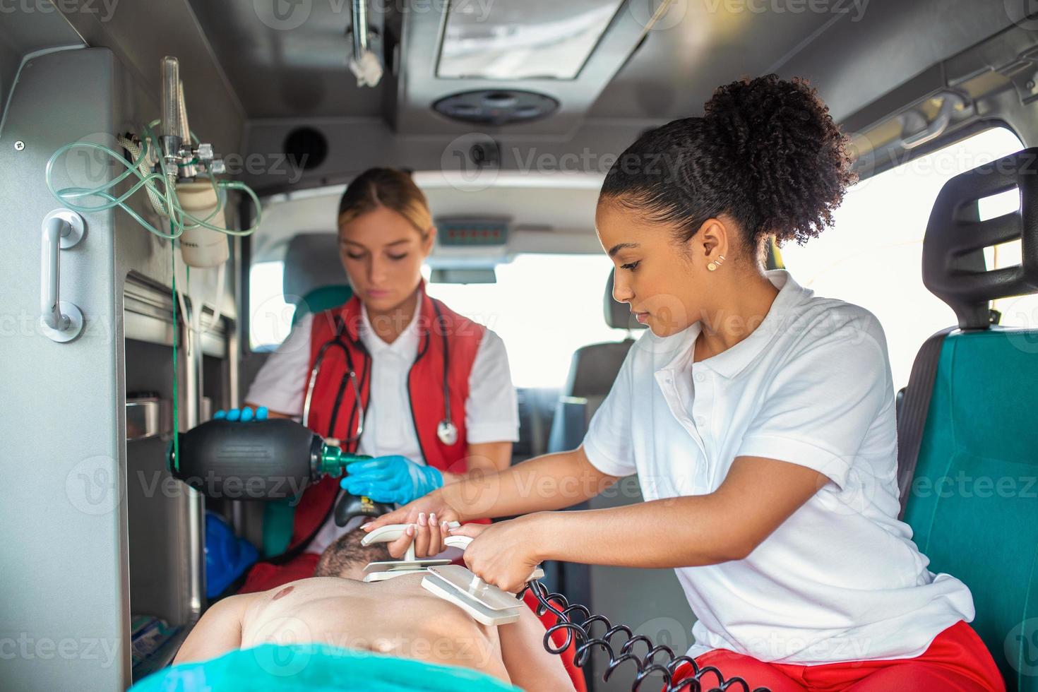 Paramedic using defibrillator AED in conducting a basic cardiopulmonary resuscitation. Emergency Care Assistant Putting Silicone Manual Resuscitators in an Ambulance. photo