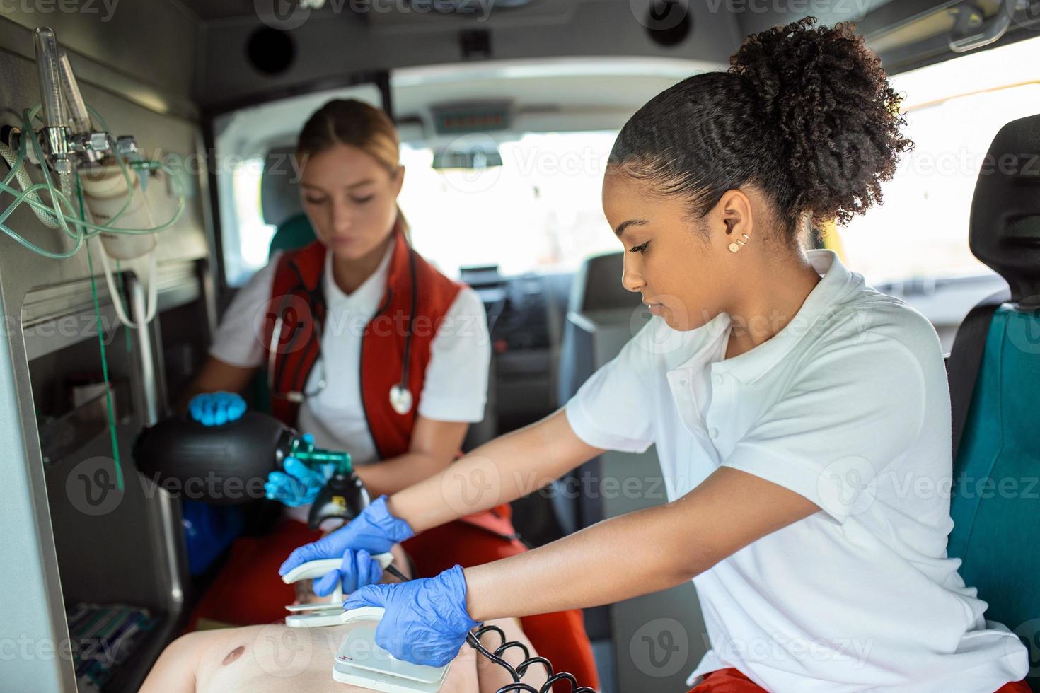 Paramedic using defibrillator  AED  in conducting a basic cardiopulmonary resuscitation. Emergency Care Assistant Putting Silicone Manual Resuscitators in an Ambulance. photo