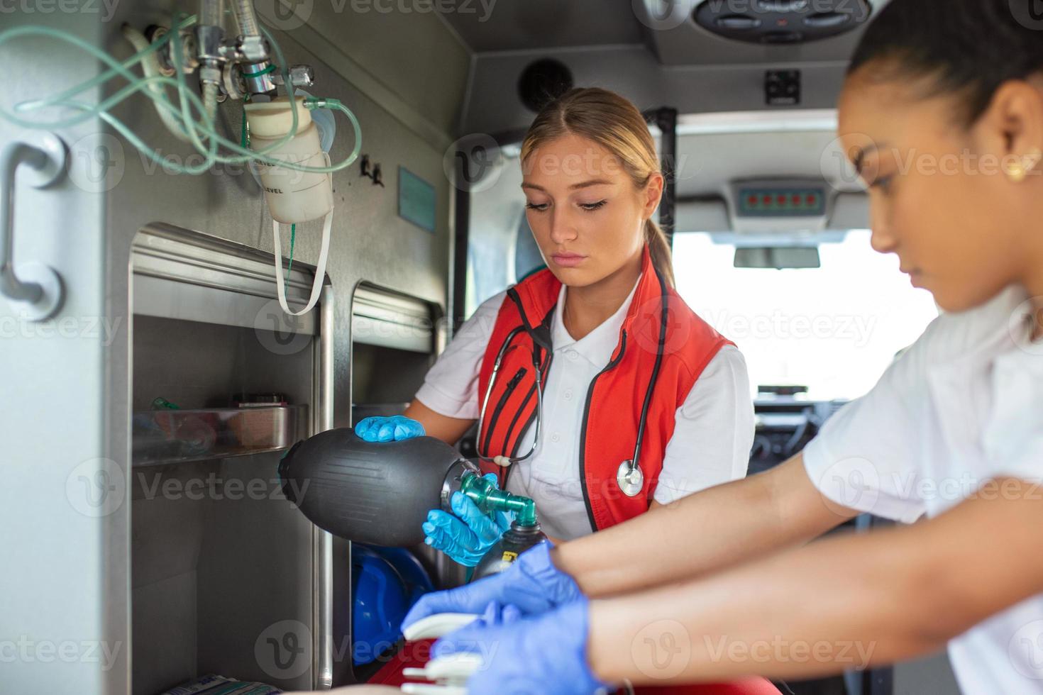 Paramedic using defibrillator AED in conducting a basic cardiopulmonary resuscitation. Emergency Care Assistant Putting Silicone Manual Resuscitators in an Ambulance. photo