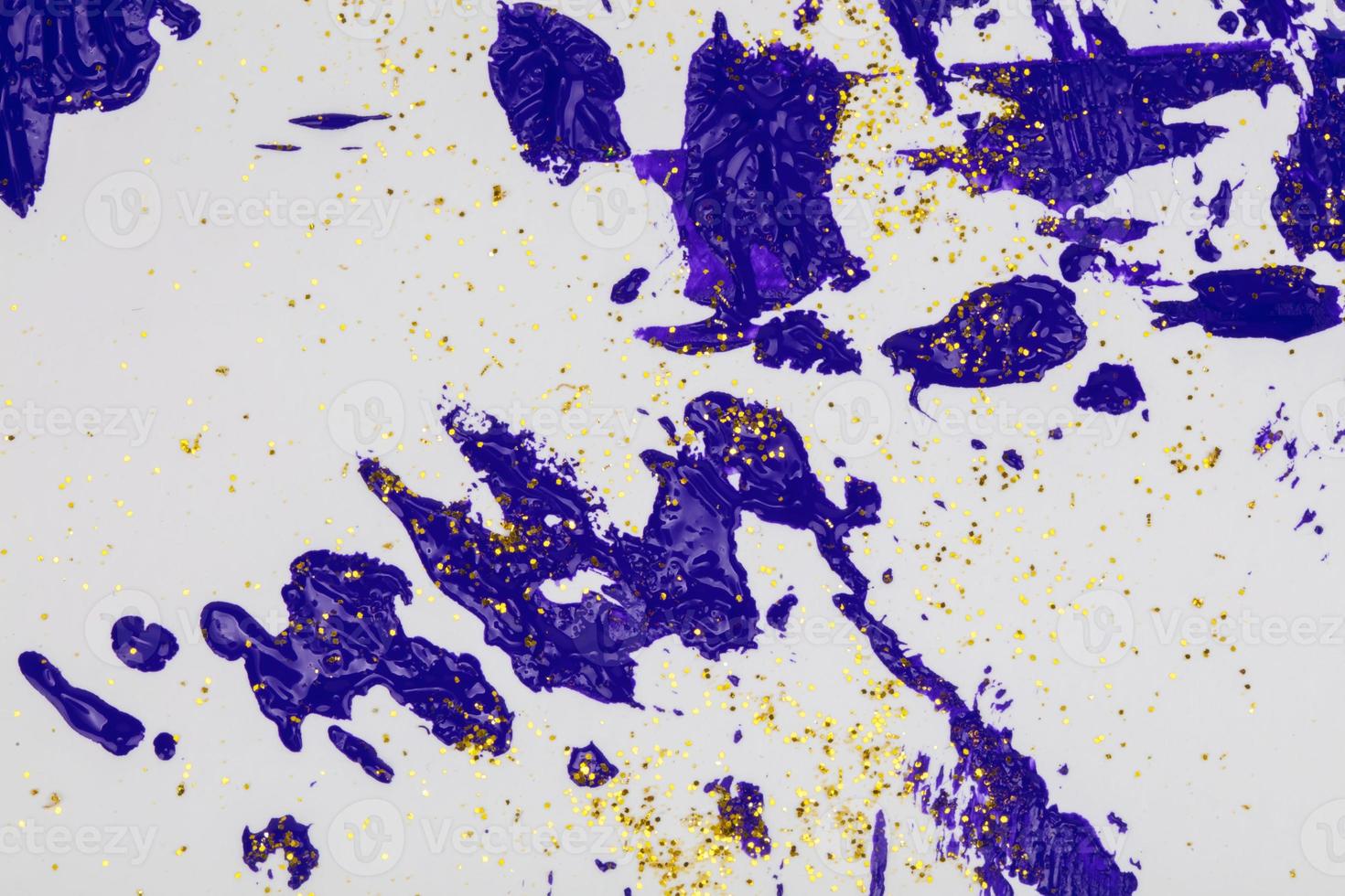 On a white background, blue splashes of acrylic paint with gold sparkles. photo