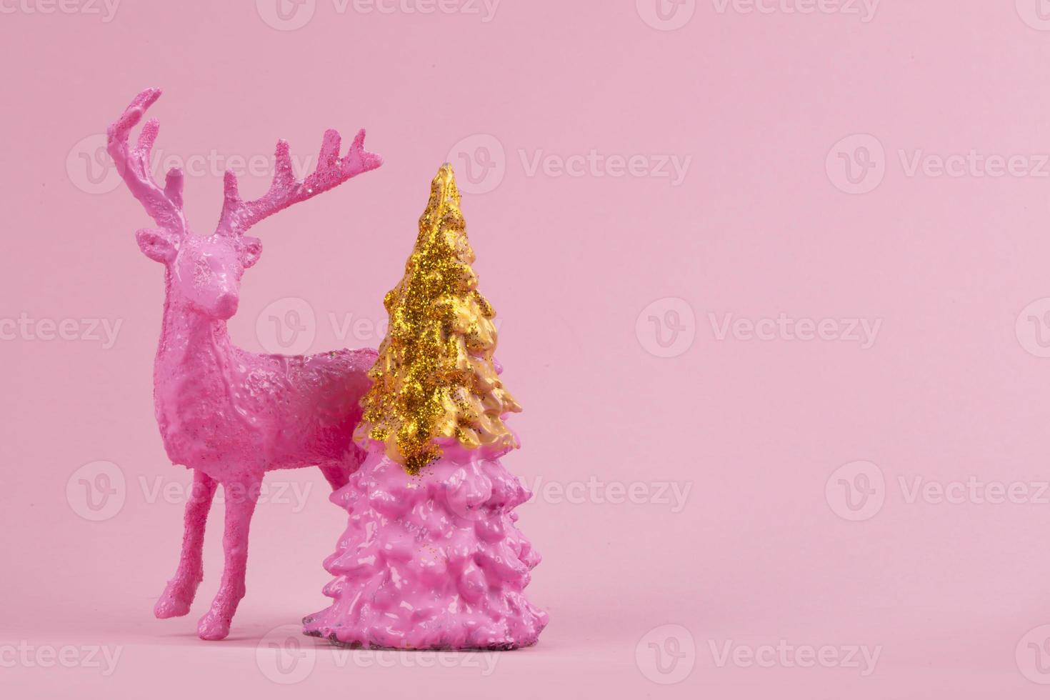 Festive minimalistic Christmas background. On a pink background, a pink deer and a gilded Christmas tree. photo