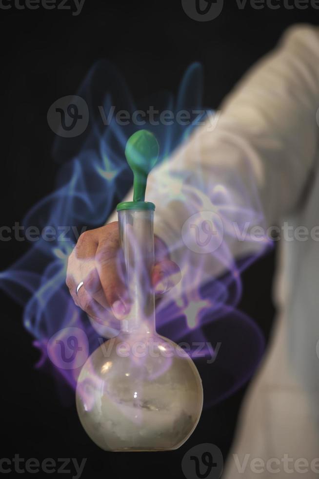 The hand of a scientist holds a flask with a chemical substance against the background of a magical glow. photo