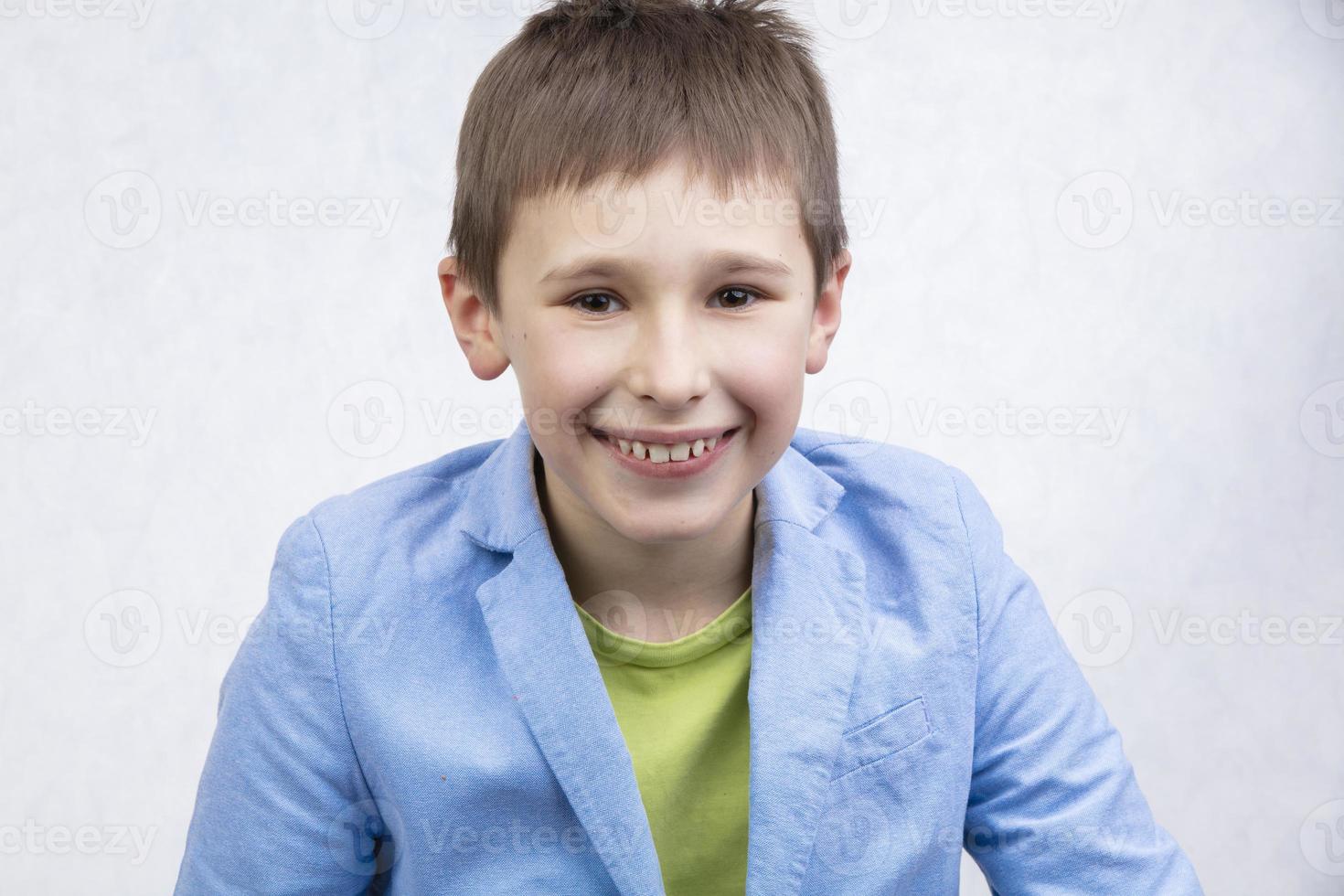 A handsome boy in a blue jacket is smiling and looking at the camera. photo