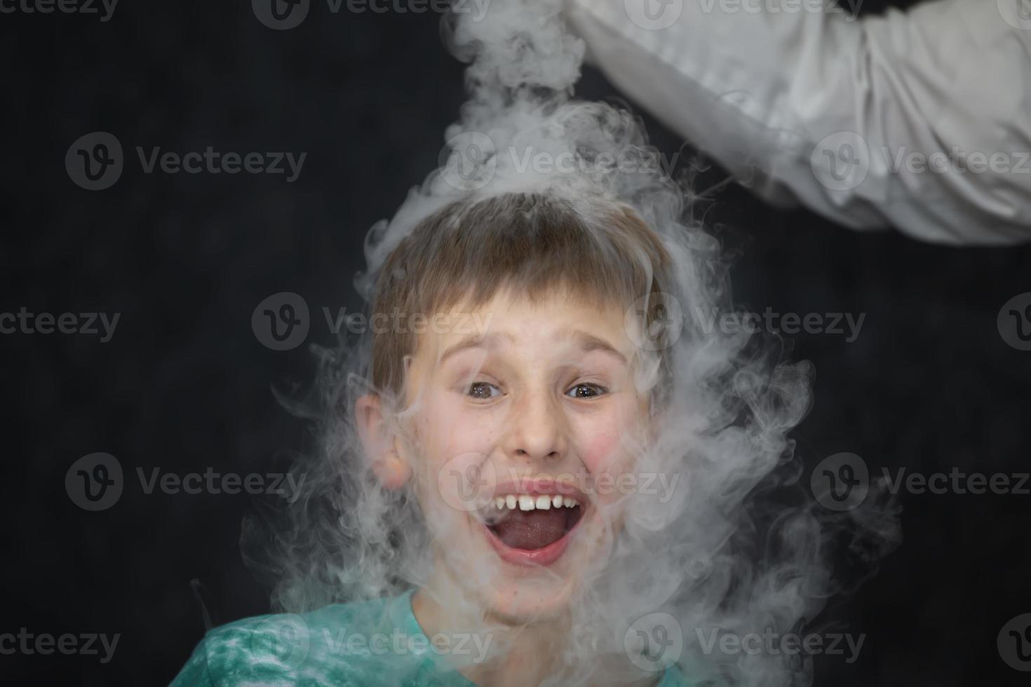 The child is a participant in scientific experiments. A boy in liquid nitrogen smoke. photo