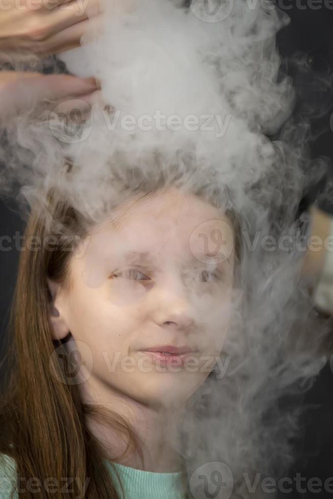 The child is a participant in scientific experiments. Girl in liquid nitrogen smoke. photo