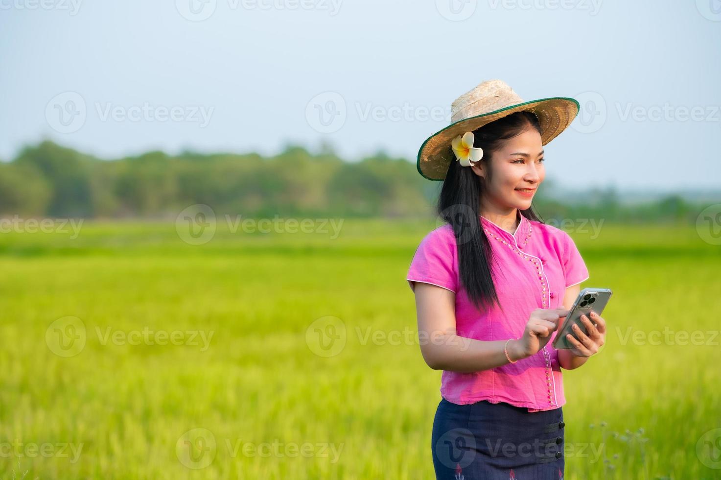 Asian female farmer holding tablet walking in rice field to store information photo