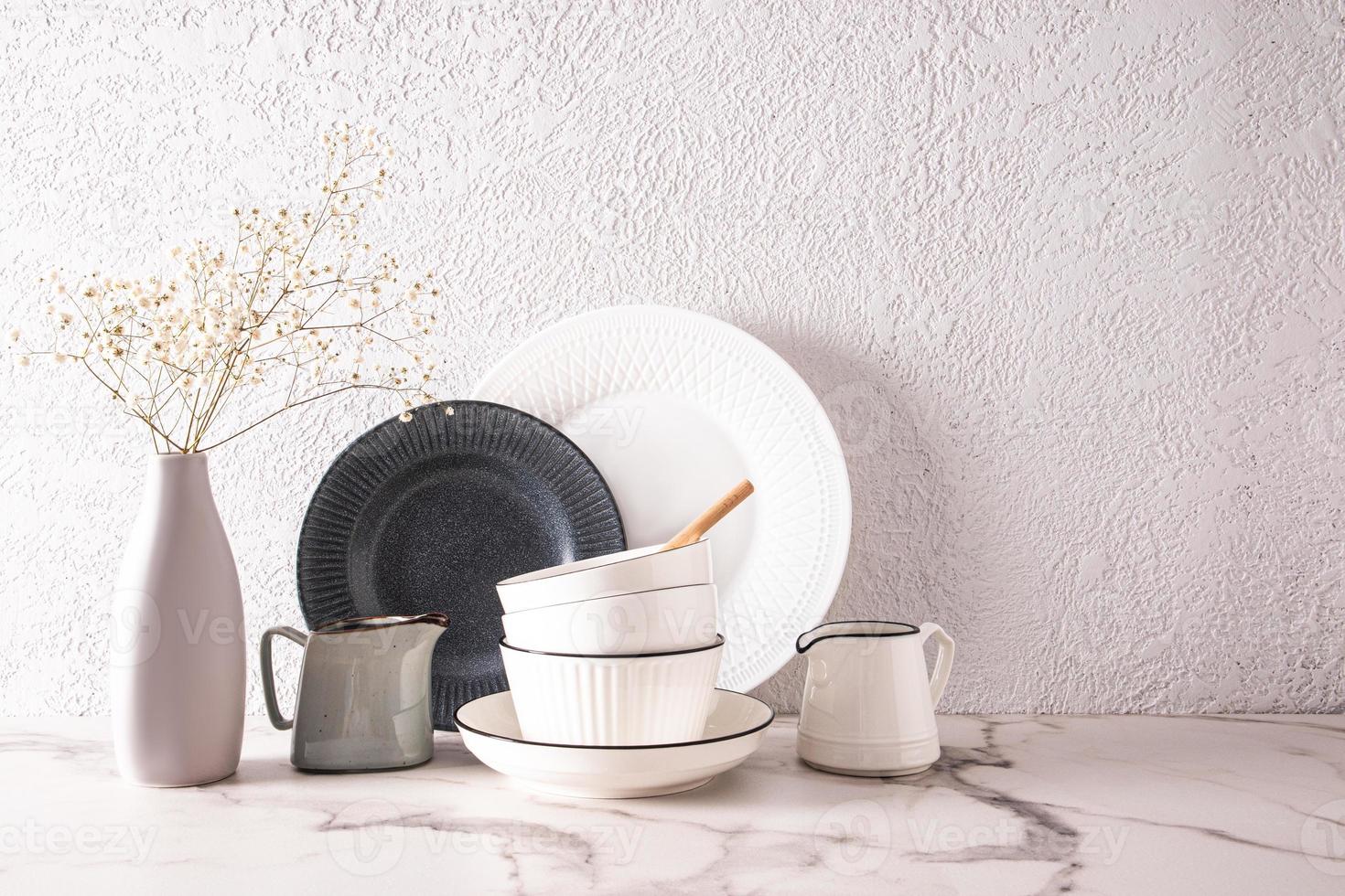 hermosa blanco elegante antecedentes parte de el cocina encimera con cerámico bochas, platos y un florero de flores un Copiar espacio. foto