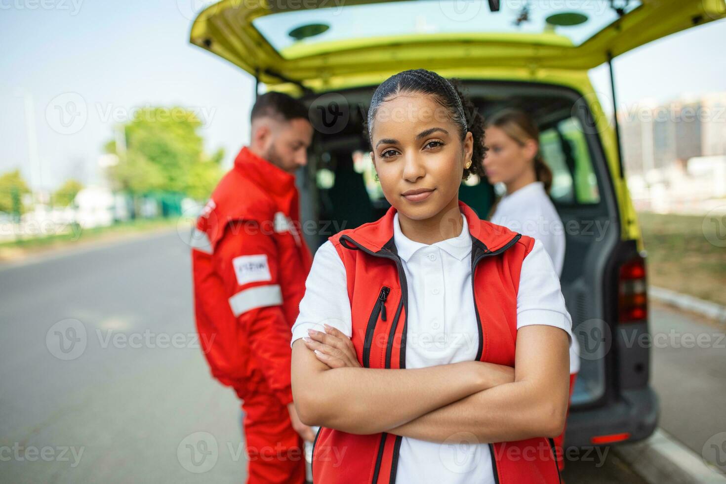 Young female african american paramedic standing rear of the ambulance. paramedics by the ambulance. Two paramedics taking out strecher from ambulance photo