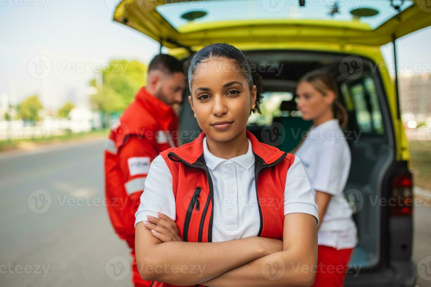 Young female african american paramedic standing rear of the ambulance. paramedics by the ambulance. Two paramedics taking out strecher from ambulance photo