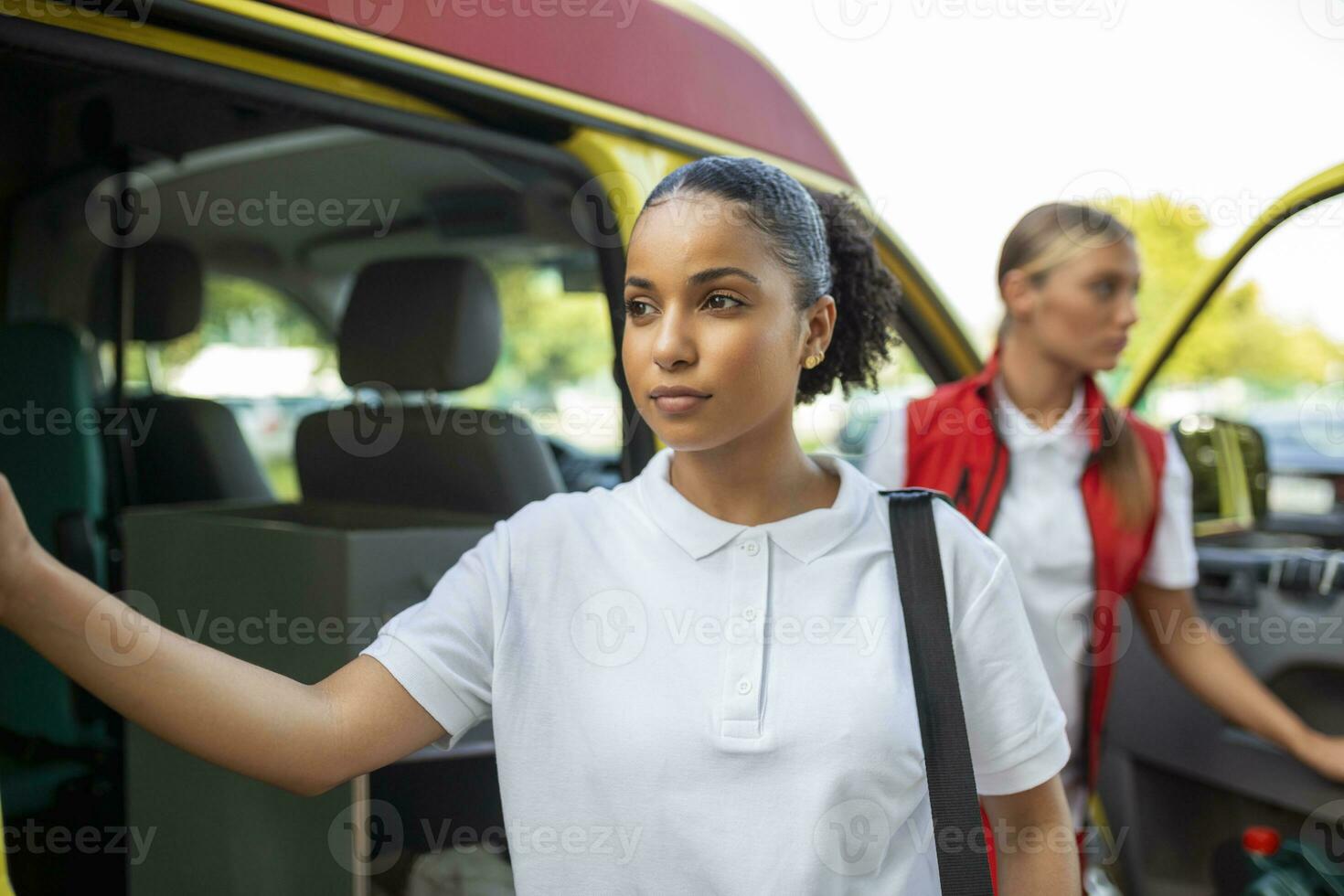 Paramedic nurse and emergency doctor at ambulance with kit. a paramedic, standing at the rear of an ambulance, by the open doors. photo