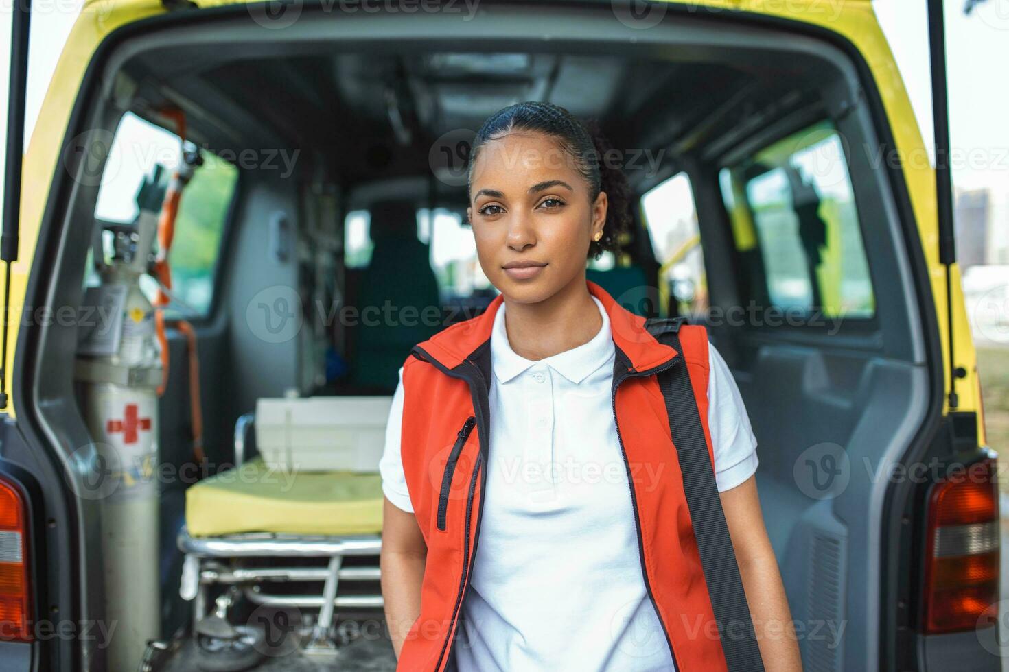 Ambulance staff member emerges from the back of an ambulance with her emergency backpack , and vital signs monitor . photo