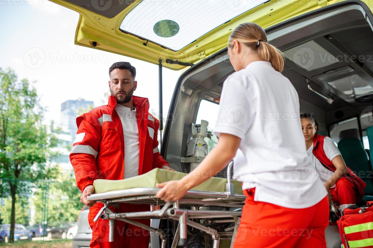 paramedics with a stretcher near an ambulance. Paramedics in uniform taking stretcher out the ambulance car photo