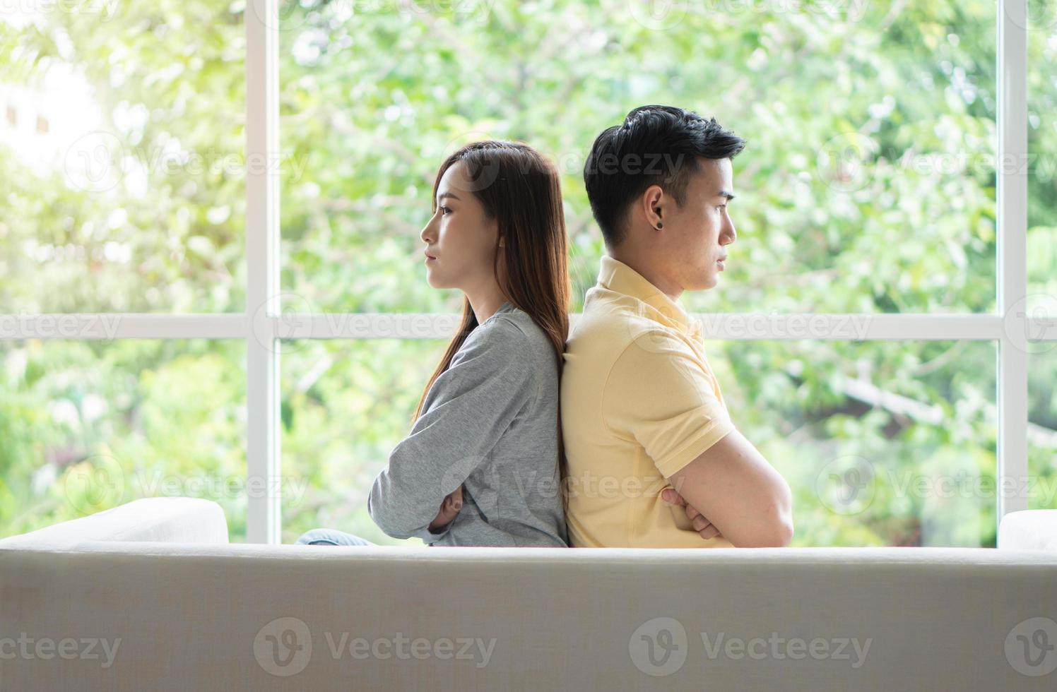 Unhappy Couple sitting behind each other on the couch and avoid talking or looking at each other, Cause of relationship problems and having misunderstanding or disagreement. Family problems concept photo