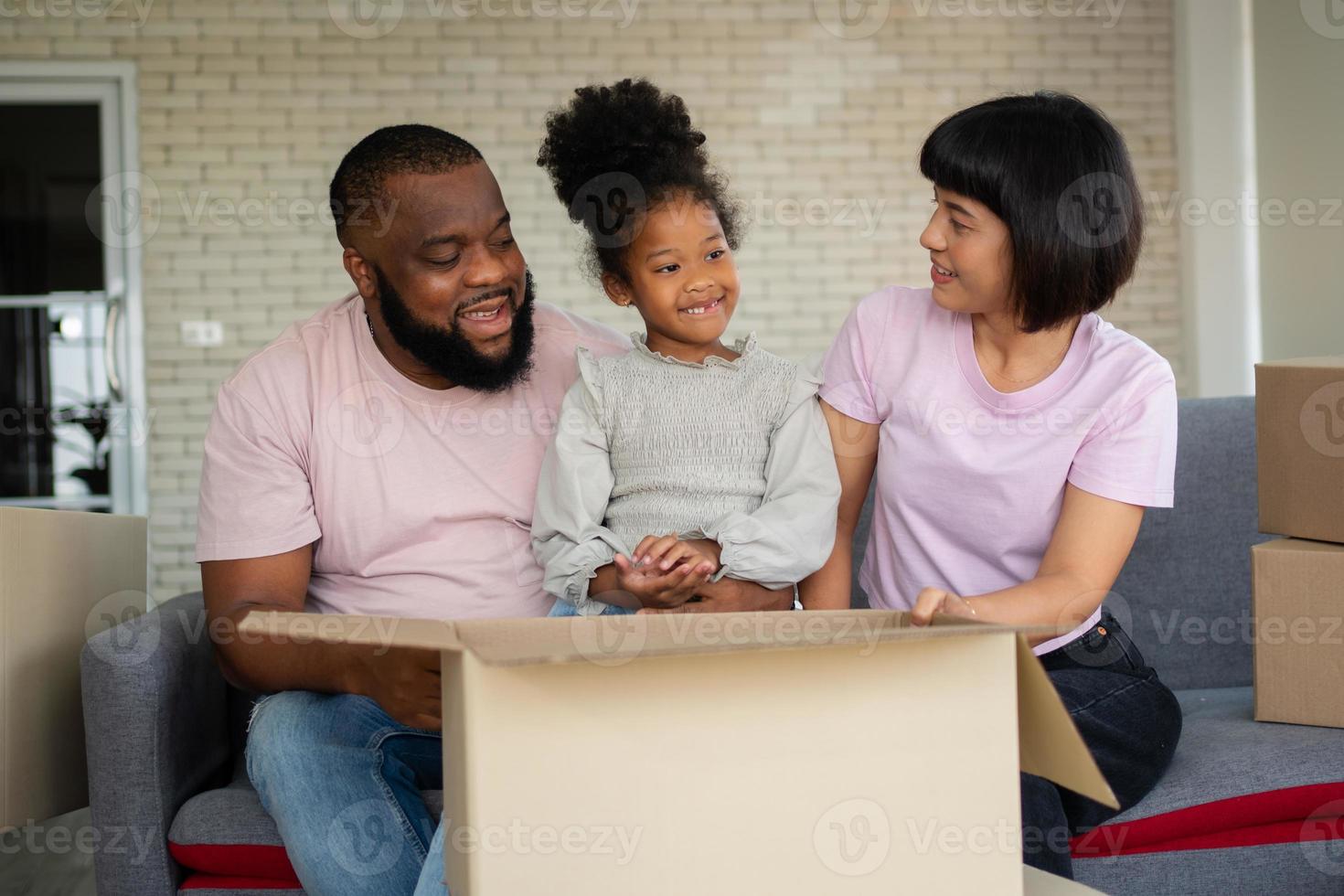 Mixed Race families are sitting on the sofa for rest after moving to a new house on the first day after buying real estate.  Concept of starting a new life for a new family. photo