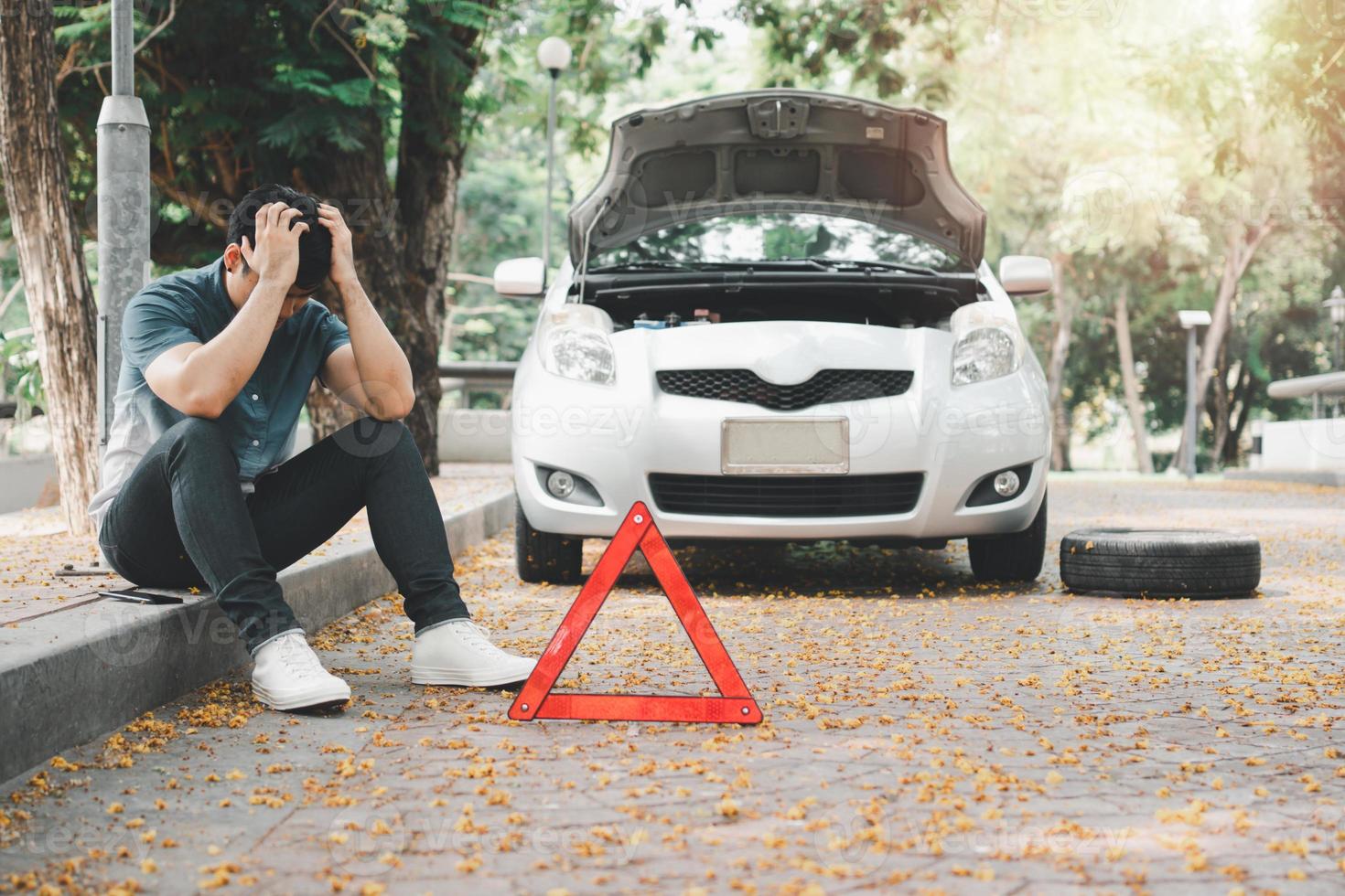 Asian woman sitting beside car after a car breakdown on street. Concept of vehicle engine problem or accident and emergency help from Professional mechanic photo