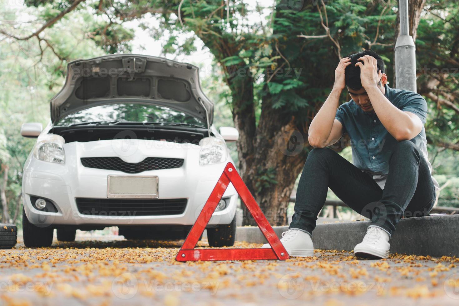 hombre asiático que usa un teléfono inteligente para obtener ayuda después de una avería en el automóvil en la calle. concepto de problema del motor del vehículo o accidente y ayuda de emergencia de un mecánico profesional foto