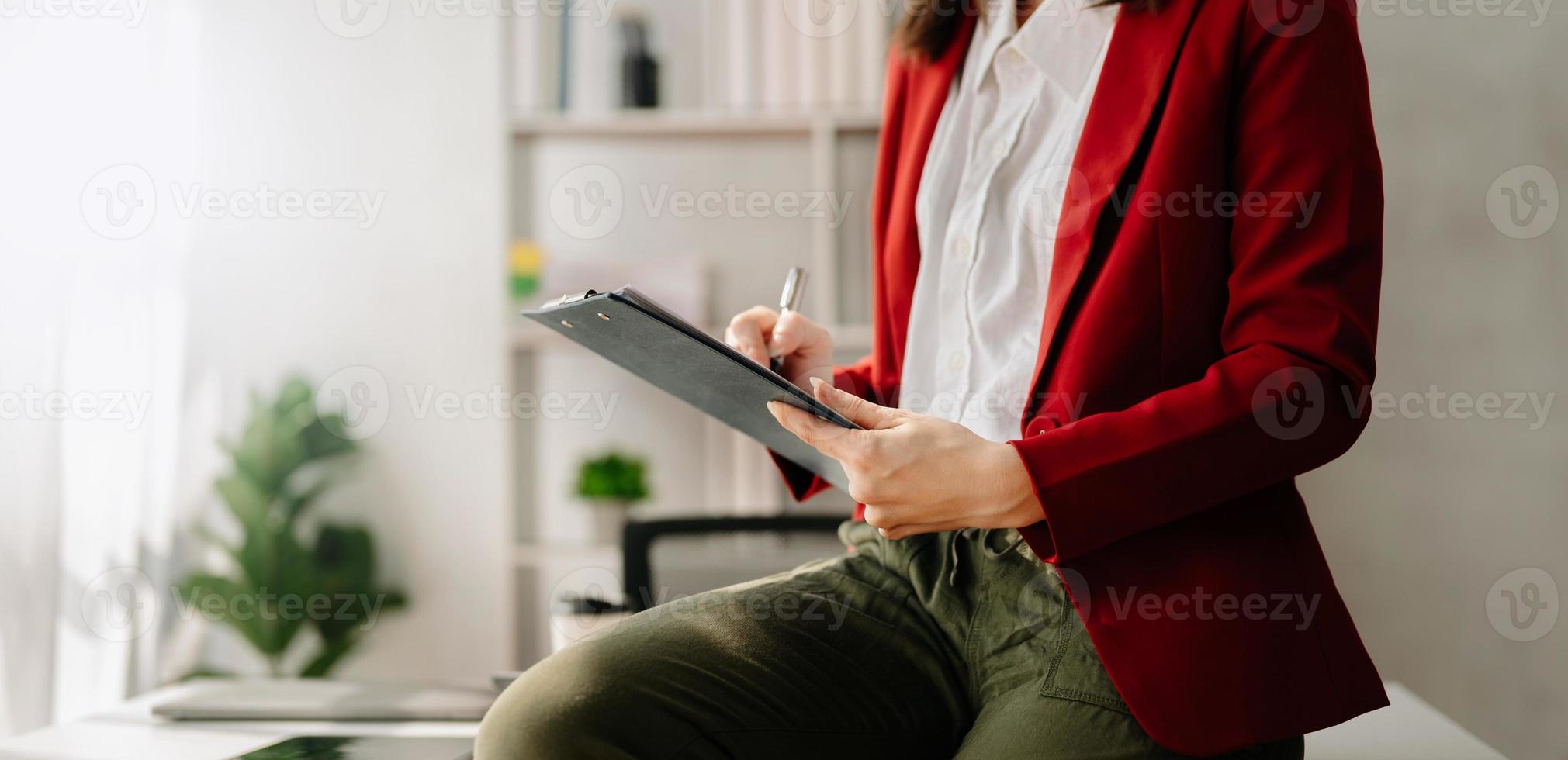 business documents on office table with smart phone and digital tablet and graph financial and woman working at office photo