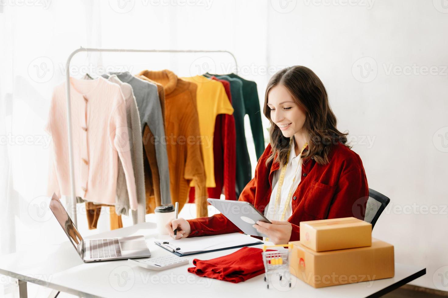 Fashion blogger concept, Young Asian women selling clothes on video streaming.Startup small business SME, using smartphone or tablet taking receive and checking photo