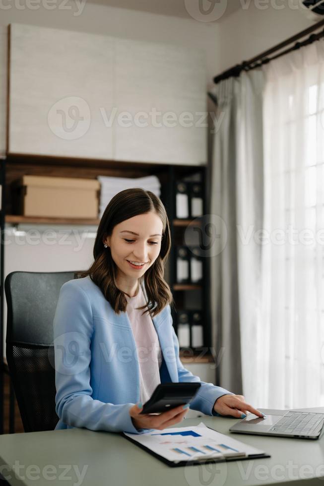 Beautiful business woman typing laptop and tablet Placed at the table at the modern office photo