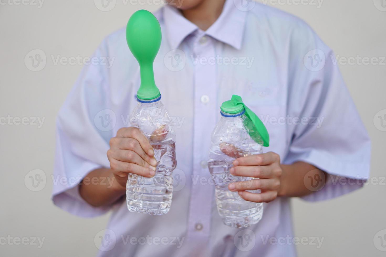 Student study  science experiment, hold two bottles with green balloons on the top of bottles. Concept, science experiment about reaction of chemical substance, vinegar and baking soda. photo