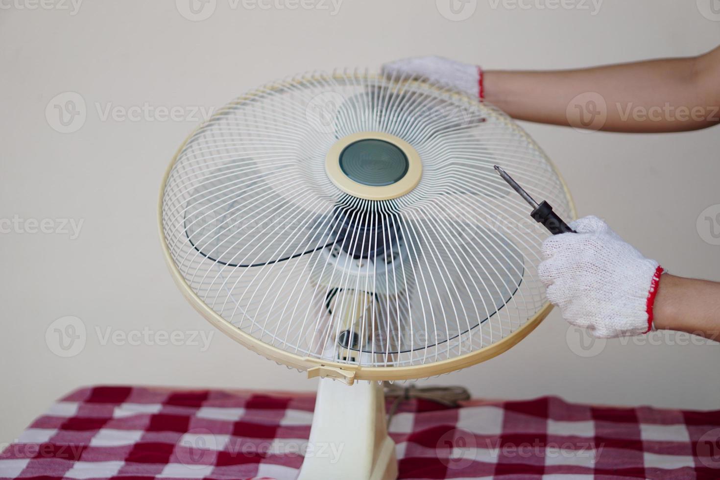 Closeup mechanic hands combine part of electric fan. Concept, maintenace appliance, electric devices in daily life, check ,repair or fix when it has problems for long using. photo
