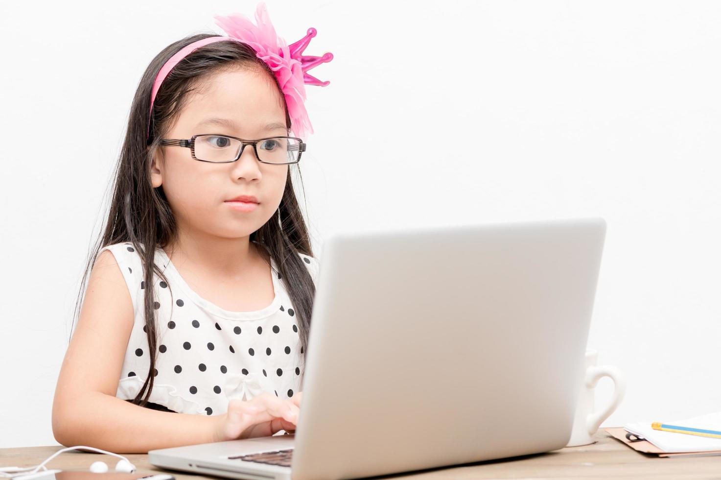 linda niña jugar computadora en blanco antecedentes foto